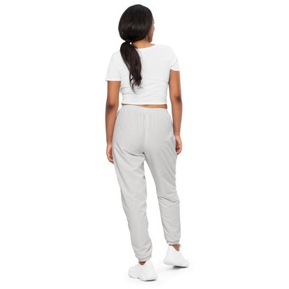 Back view of a woman wearing unisex Platinum track pants paired with a cropped white top and white sneakers.