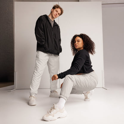 Young man and woman in unisex track pants and windbreaker, showcasing a stylish streetwear look.