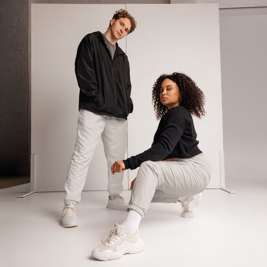 Young man and woman in unisex track pants and windbreaker, showcasing a stylish streetwear look.